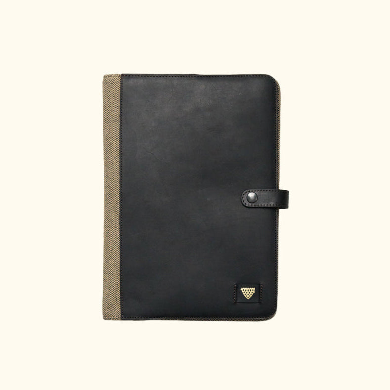 Black leather notebook with a textured brown strap on a white background