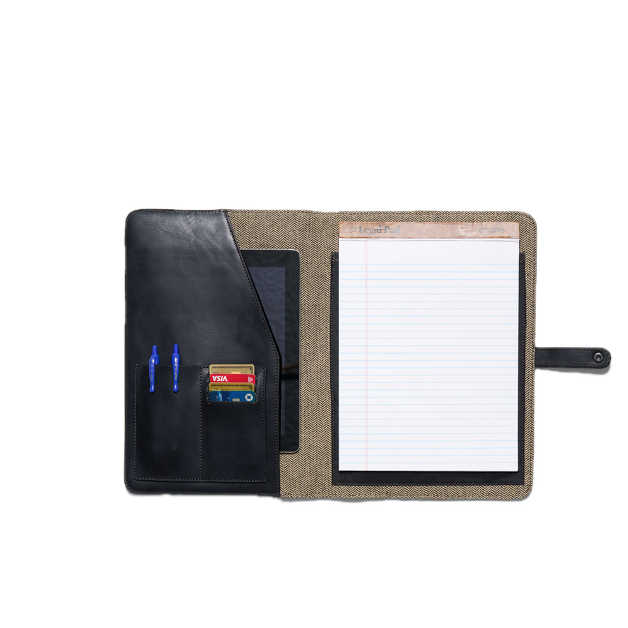 Black leather notebook with a textured brown strap on a white background