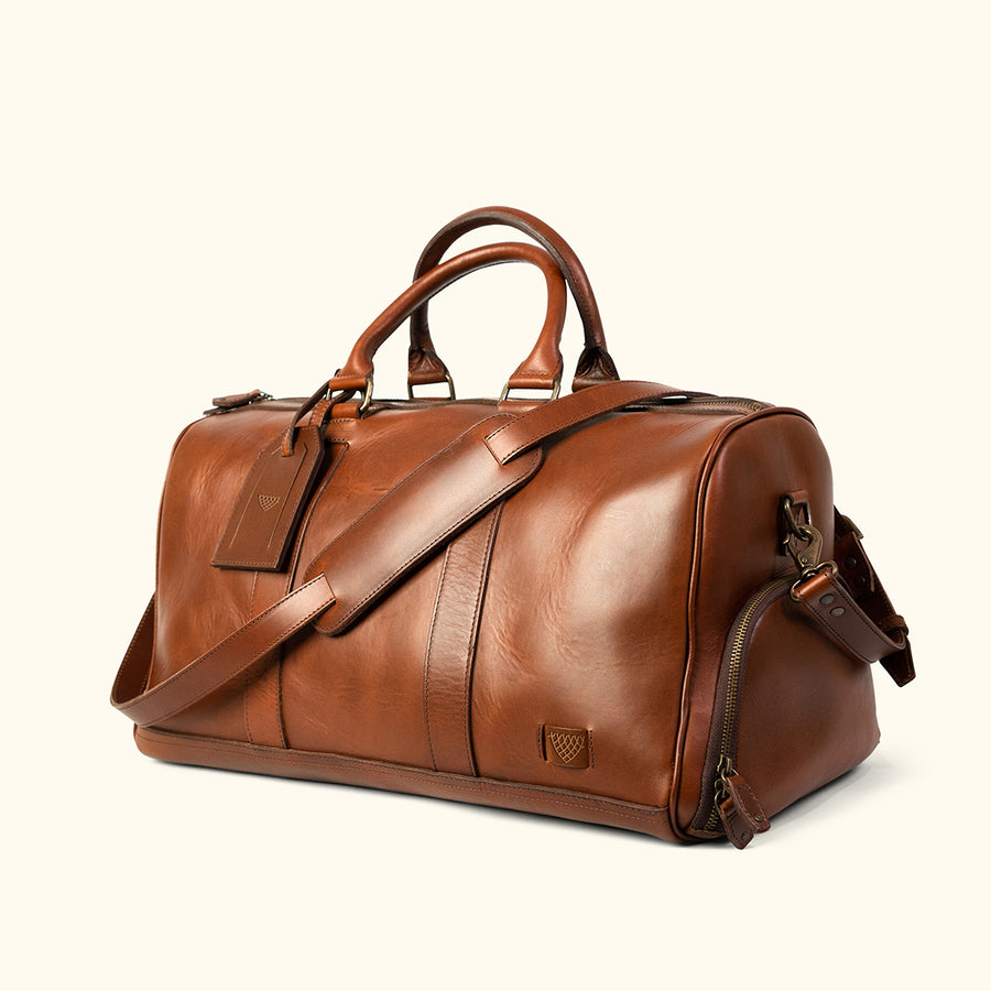 Premium tan leather weekender bag with spacious interior, reinforced stitching, and stylish brand logo.