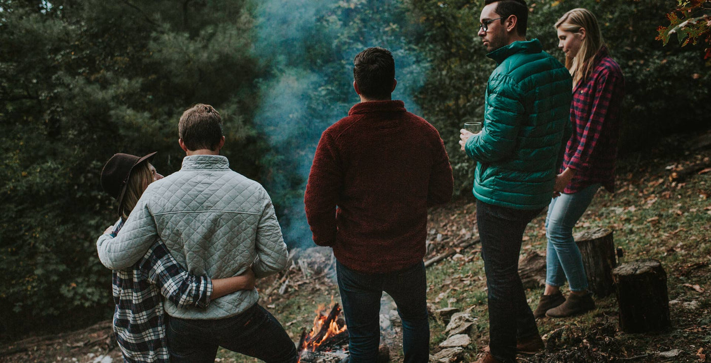 Outdoor rugged apparel standing around a campfire