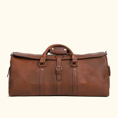 A brown full-grain leather duffle bag with a structured design and visible stitching details.