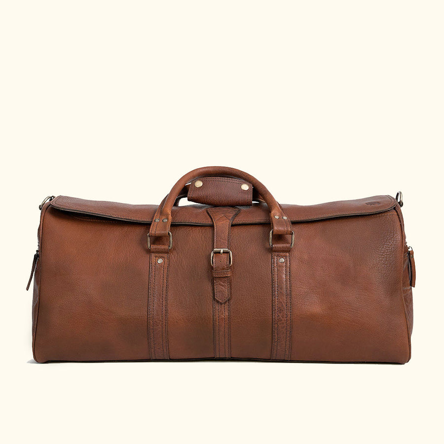 A brown full-grain leather duffle bag with a structured design and visible stitching details.