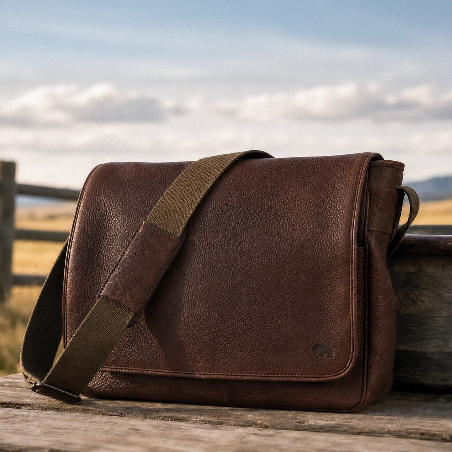 A brown full grain leather messenger bag with a structured body and a shoulder strap.