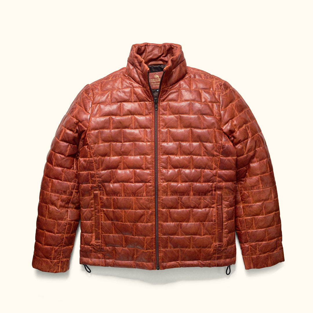A whiskey brown, full-grain leather down filled jacket with a quilted pattern and YKK antique brass zippers.