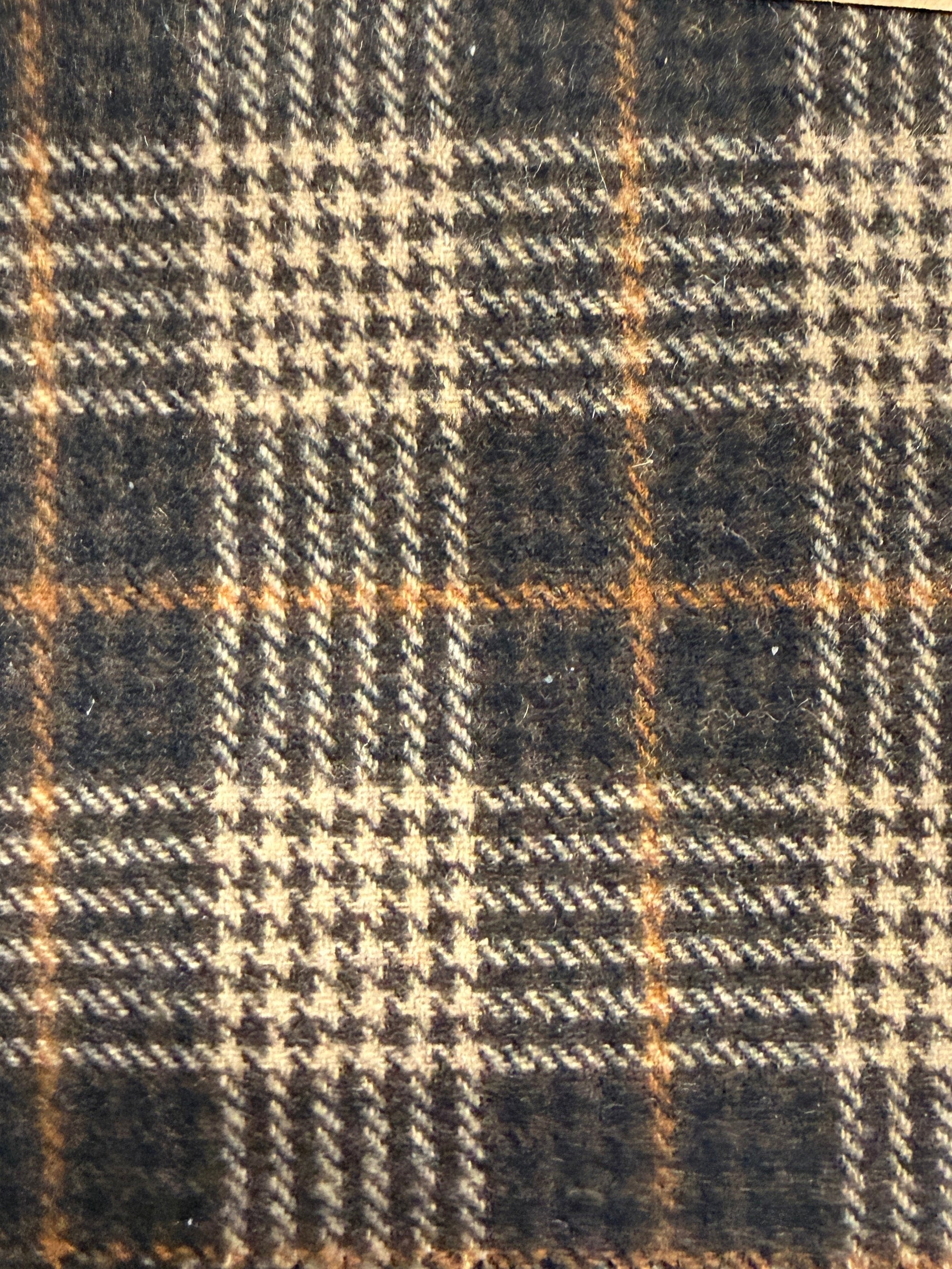 Close-up of a plaid fabric with brown, black, and beige colors.