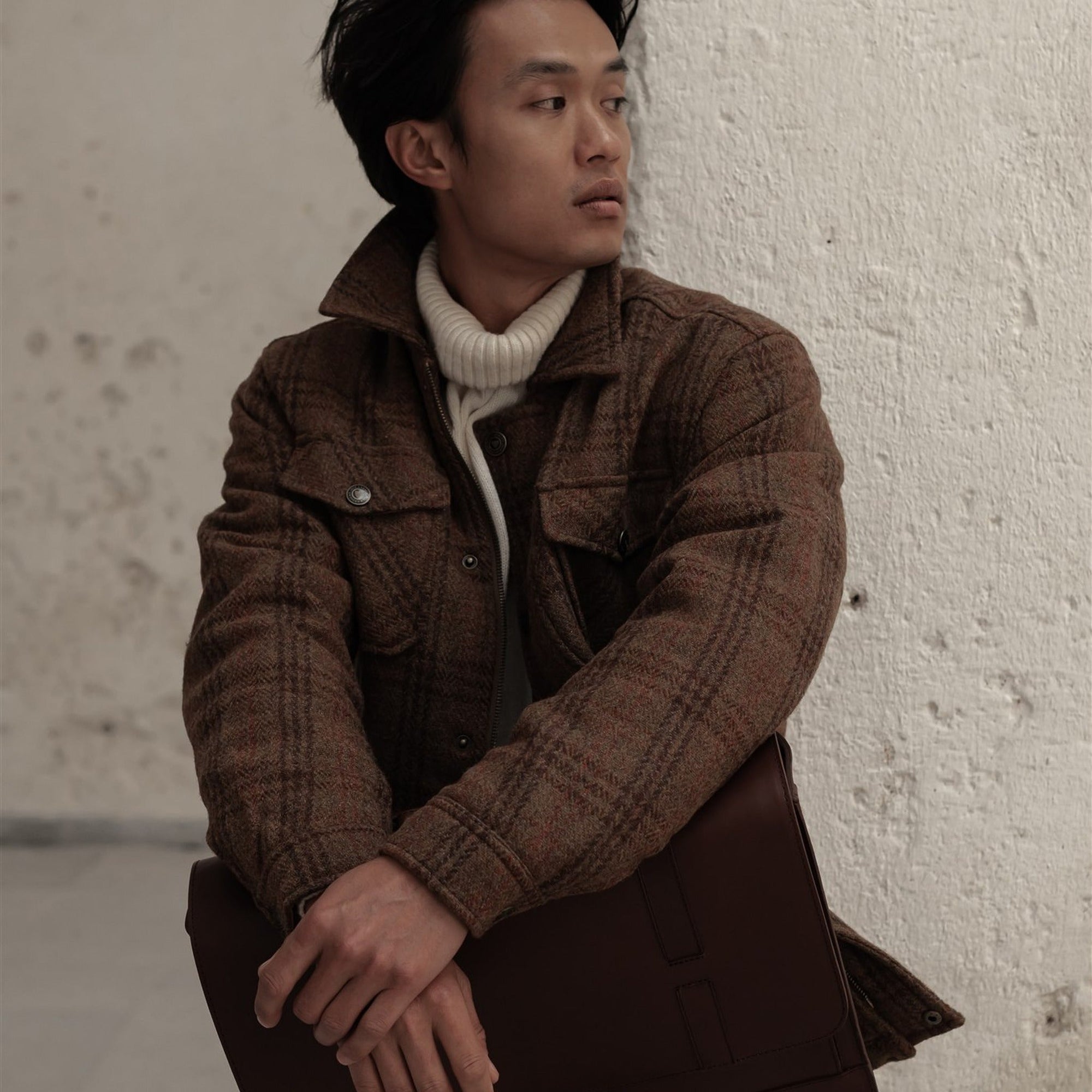 Man in the Aberdeen Wool Jacket in Dunbar Thicket looking over his shoulder by a white wall
