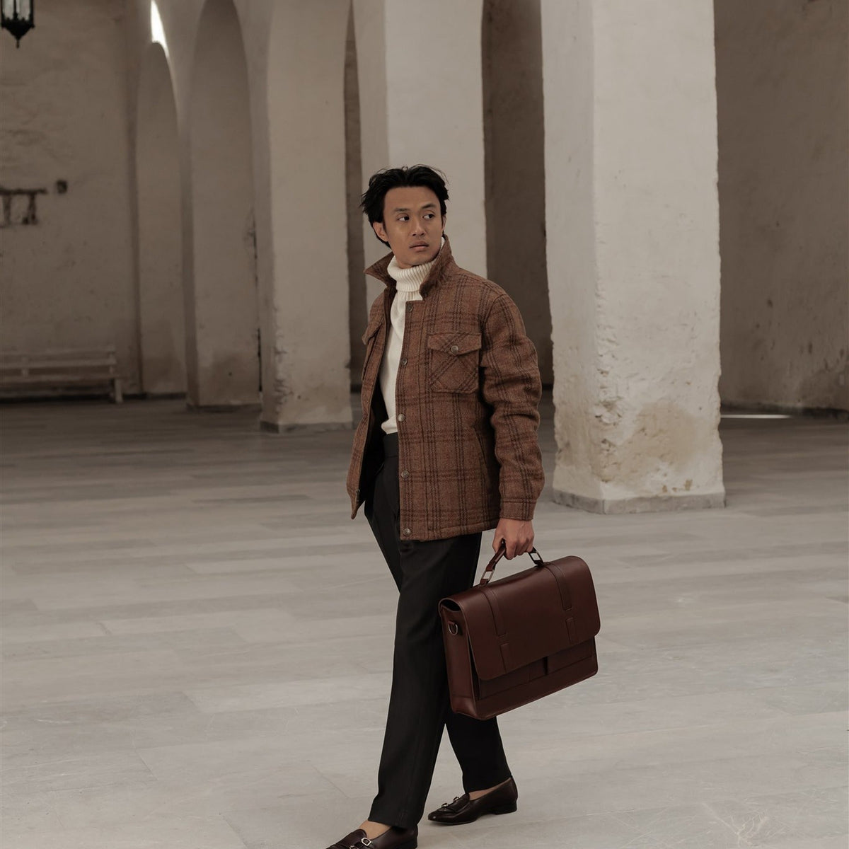 Man in the Aberdeen Wool Jacket in Dunbar Thicket walking through an arcade with a leather briefcase