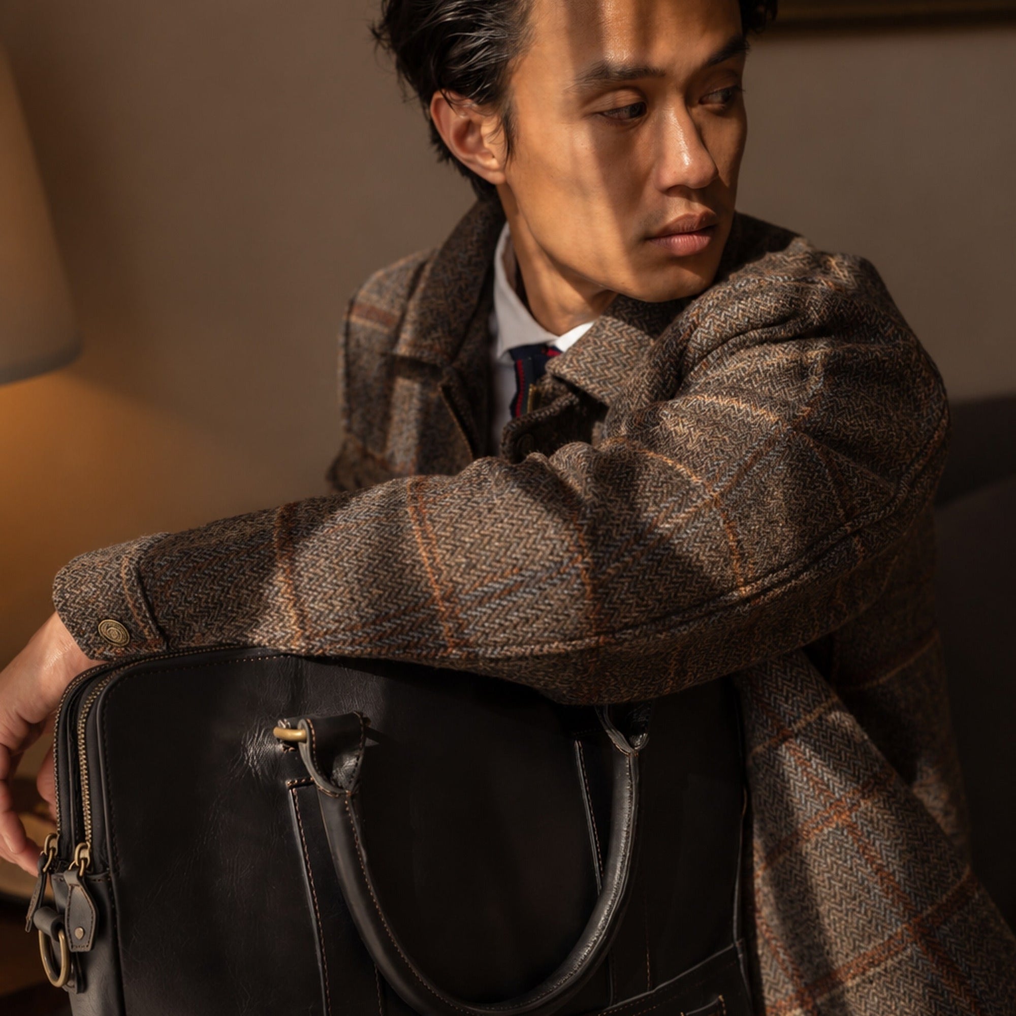 Man in the Aberdeen Wool Jacket in Grey Briar in golden-hour light with a leather briefcase