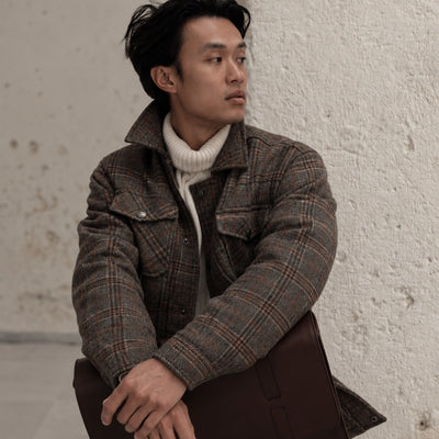 Man in the Aberdeen Wool Jacket in Grey Briar over a cream turtleneck against a white stucco wall