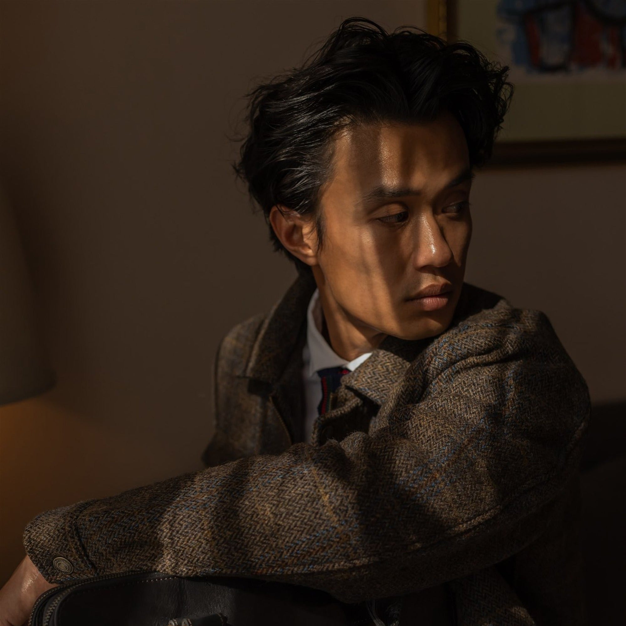 Man in the Aberdeen Wool Jacket in Thistle Bark Plaid in lamplight, holding a leather briefcase
