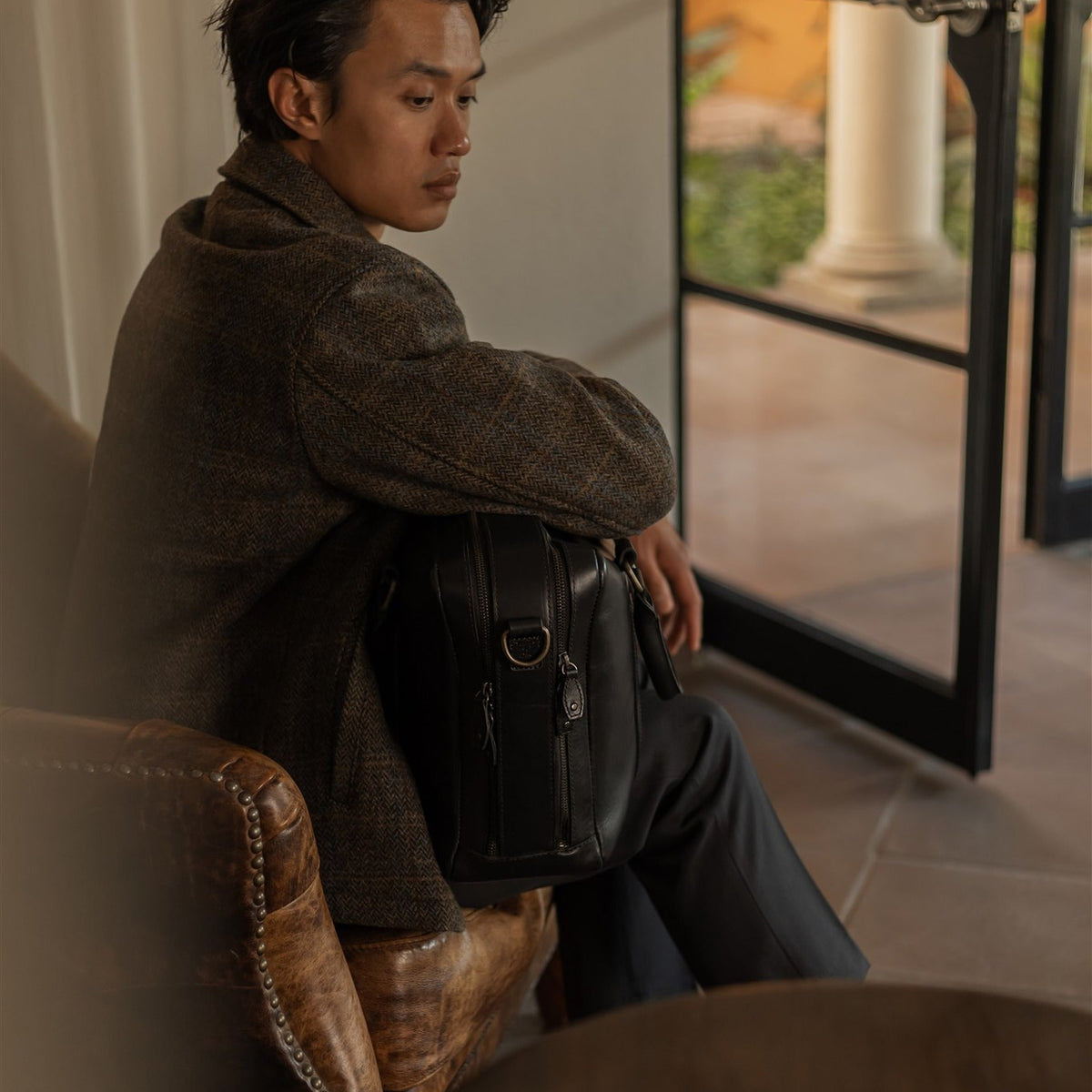 Man in the Aberdeen Wool Jacket in Thistle Bark Plaid seated by a tall window