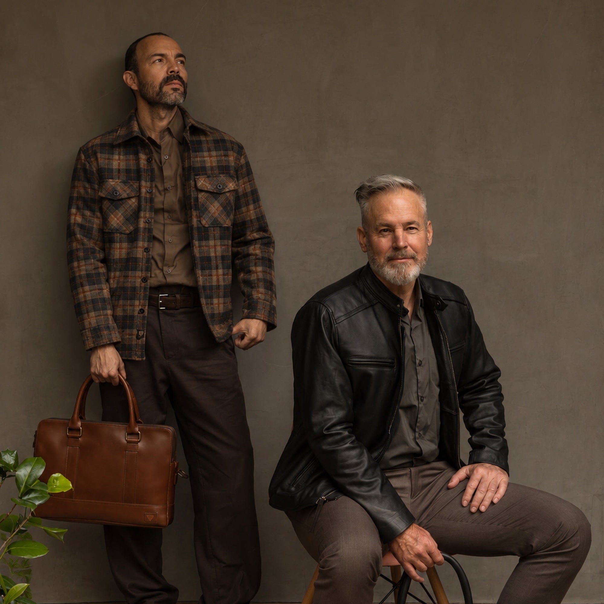 Man in the Aberdeen Wool Twill Shirt Jac in Brown Briar holding a leather briefcase beside a seated man in a black leather jacket
