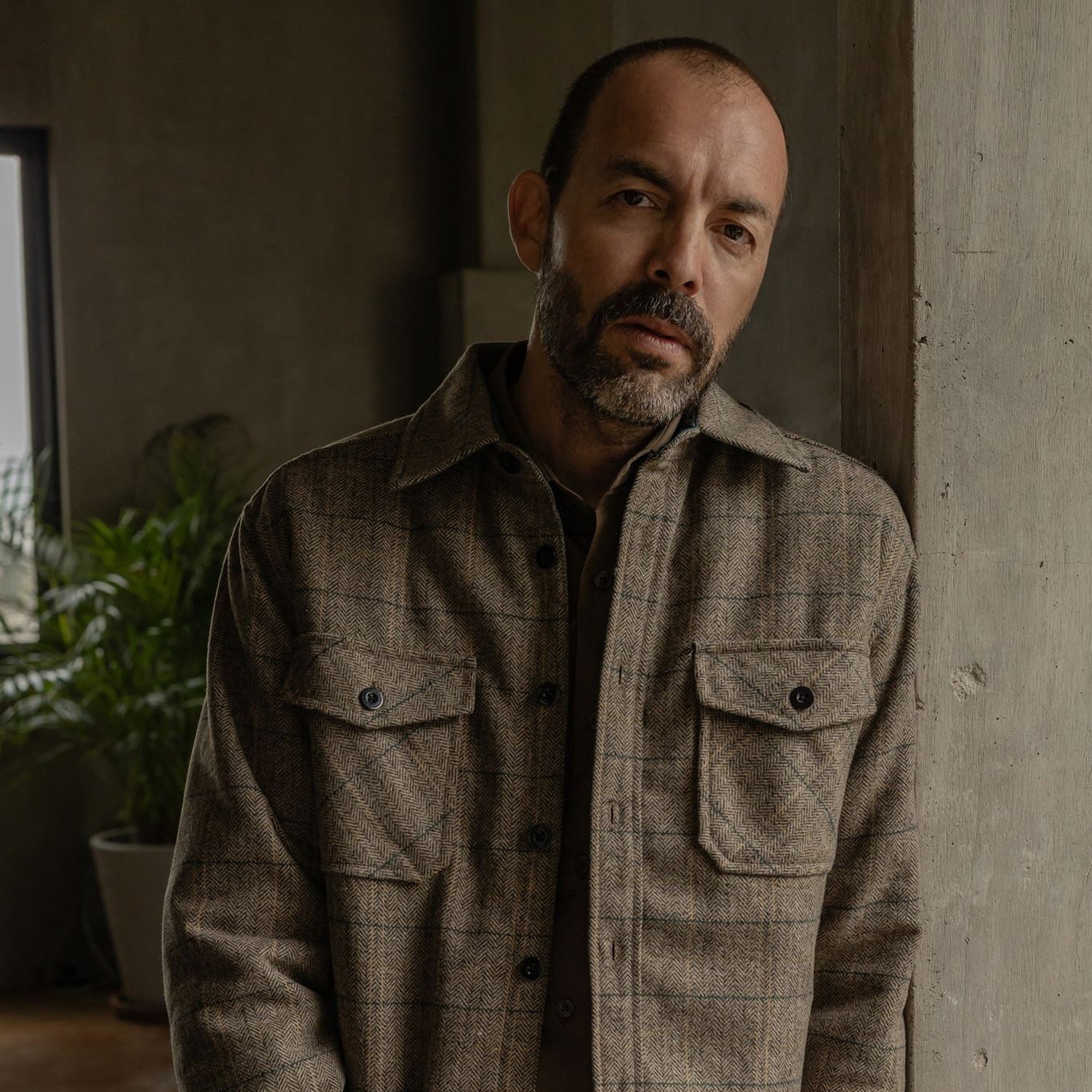 Man in the Aberdeen Wool Twill Shirt Jac in Thistle Grove standing by a concrete wall