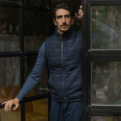 Man in the Ashton Wool Herringbone Vest in Clan Blue leaning in a steel-framed doorway