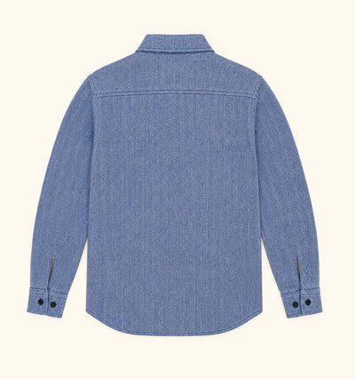 A blue denim long-sleeve button-up shirt shown from the back, laid flat against a light cream background.