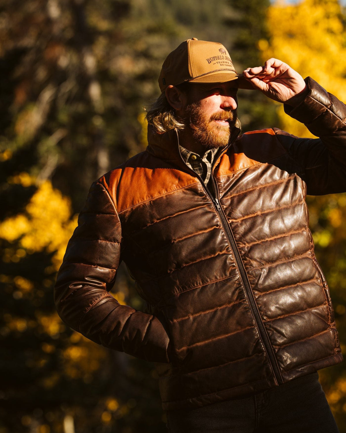 Man in a Buffalo Jackson quilted leather down jacket tipping his cap among golden aspens