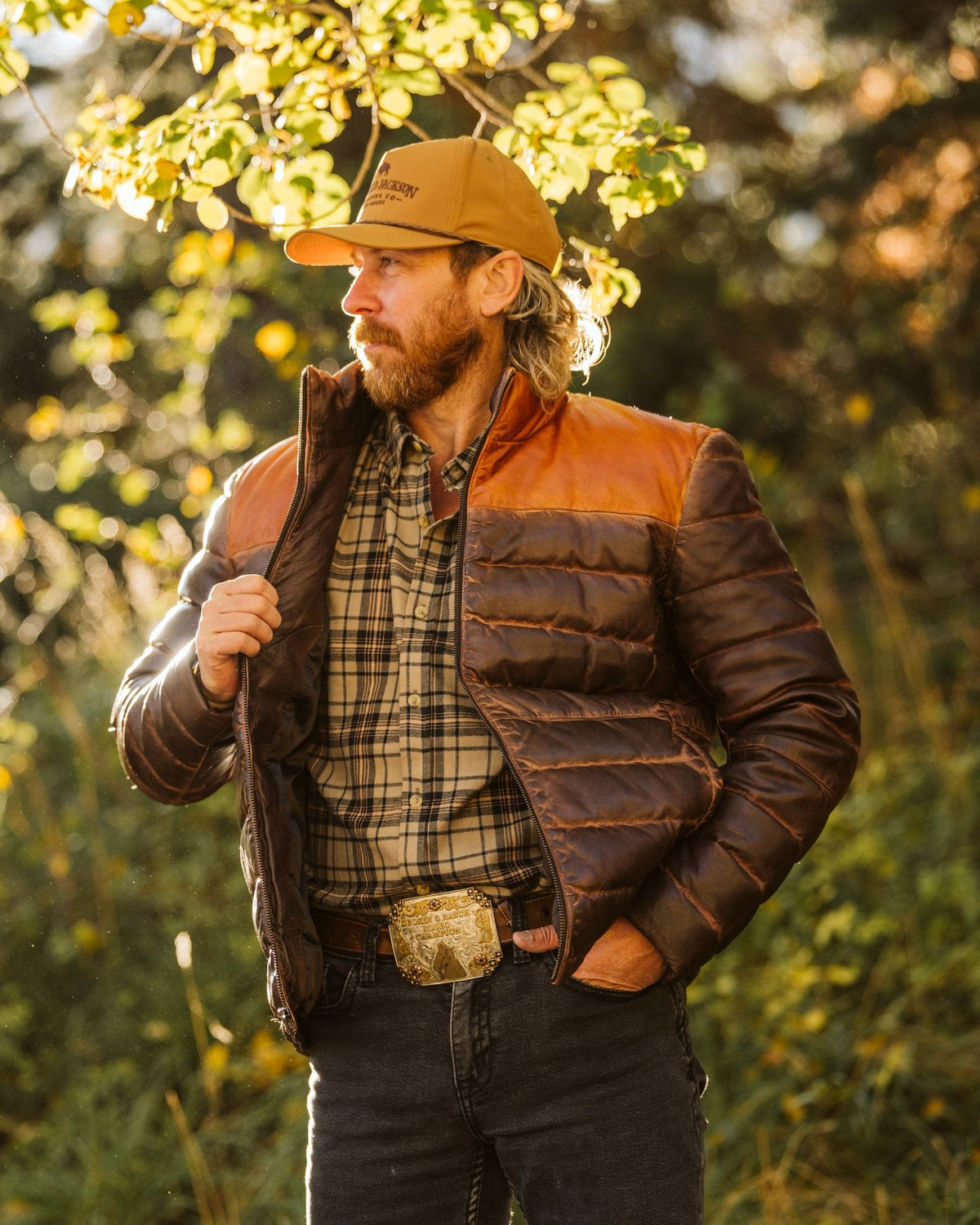 Man in a two-tone leather down jacket and plaid flannel under autumn aspen leaves