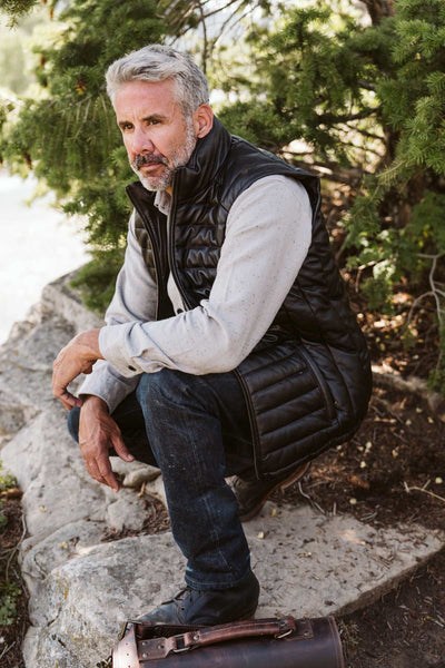 Front view of a modern black leather puffer vest, featuring a comfortable fit and practical pockets.