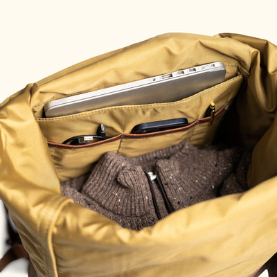 Open canvas backpack with spacious interior, holding a sweater and laptop.
