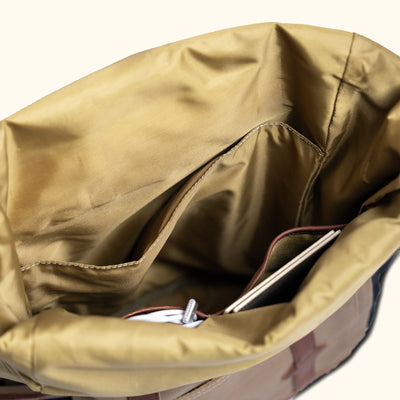 Interior of a waxed canvas rolltop backpack, featuring organized compartments for accessories.