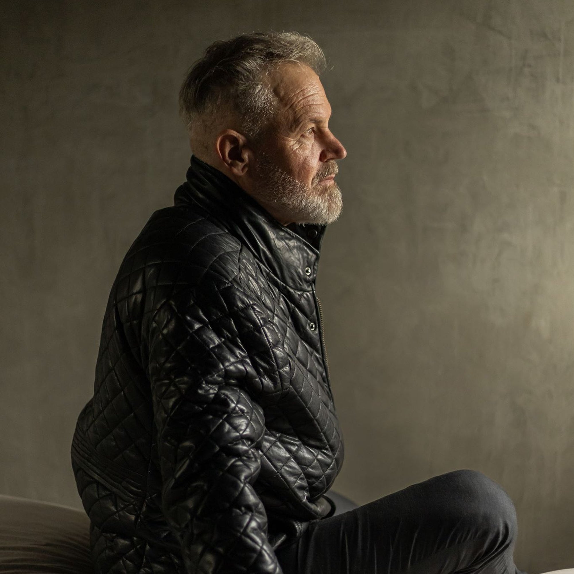Man seated in the Highlands Quilted Leather Jacket in Black, side view.