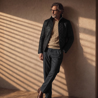 Man in the Highlands Quilted Leather Jacket in Black leaning on a sunlit wall.