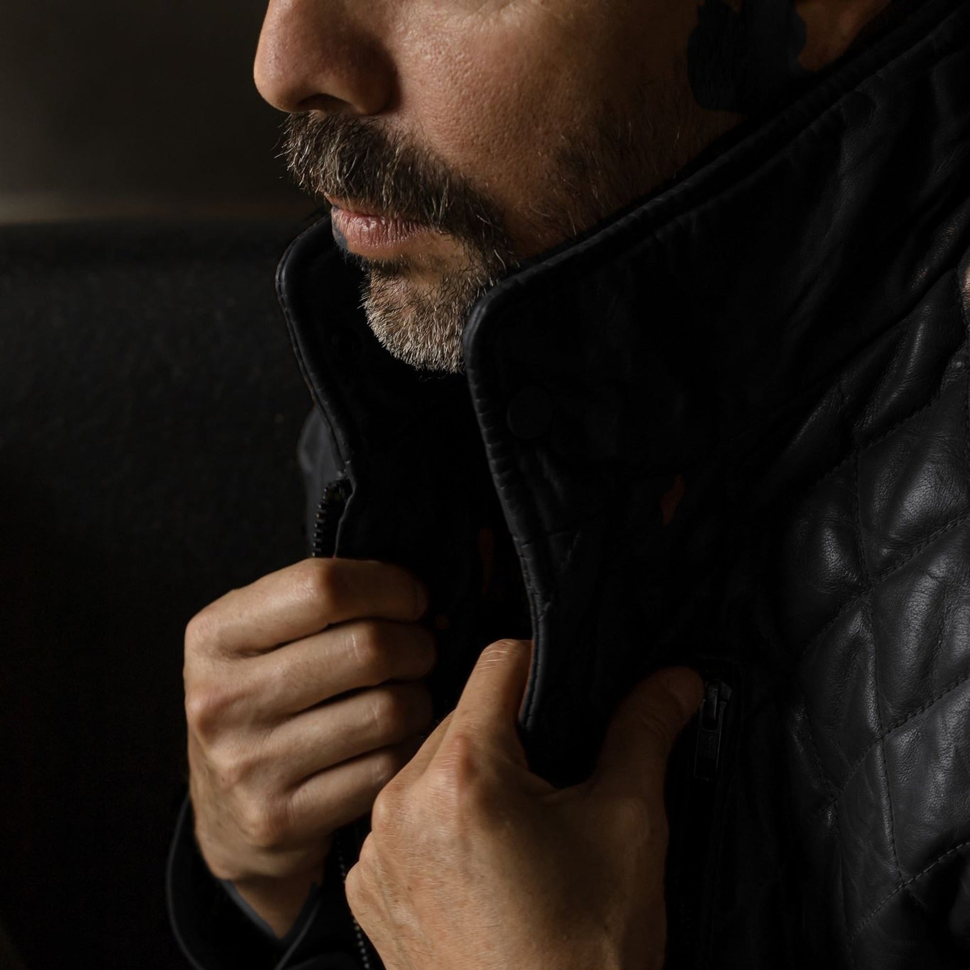 Man turning up the collar of the Highlands Quilted Leather Vest in Black.