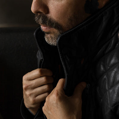 Man turning up the collar of the Highlands Quilted Leather Vest in Black.