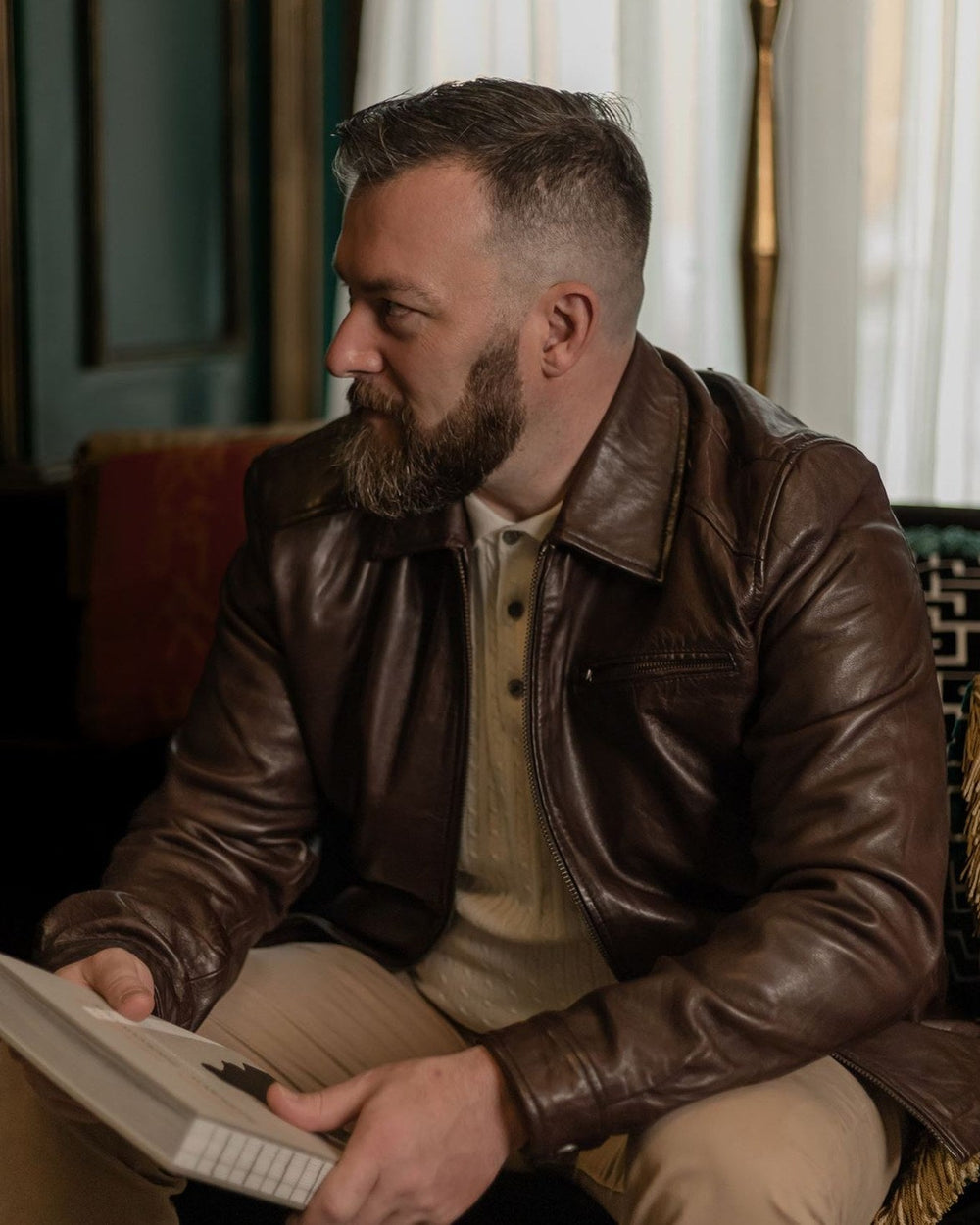 Man in the Glenwood Leather Driving Jacket in Mahogany Brown reading in a green sitting room