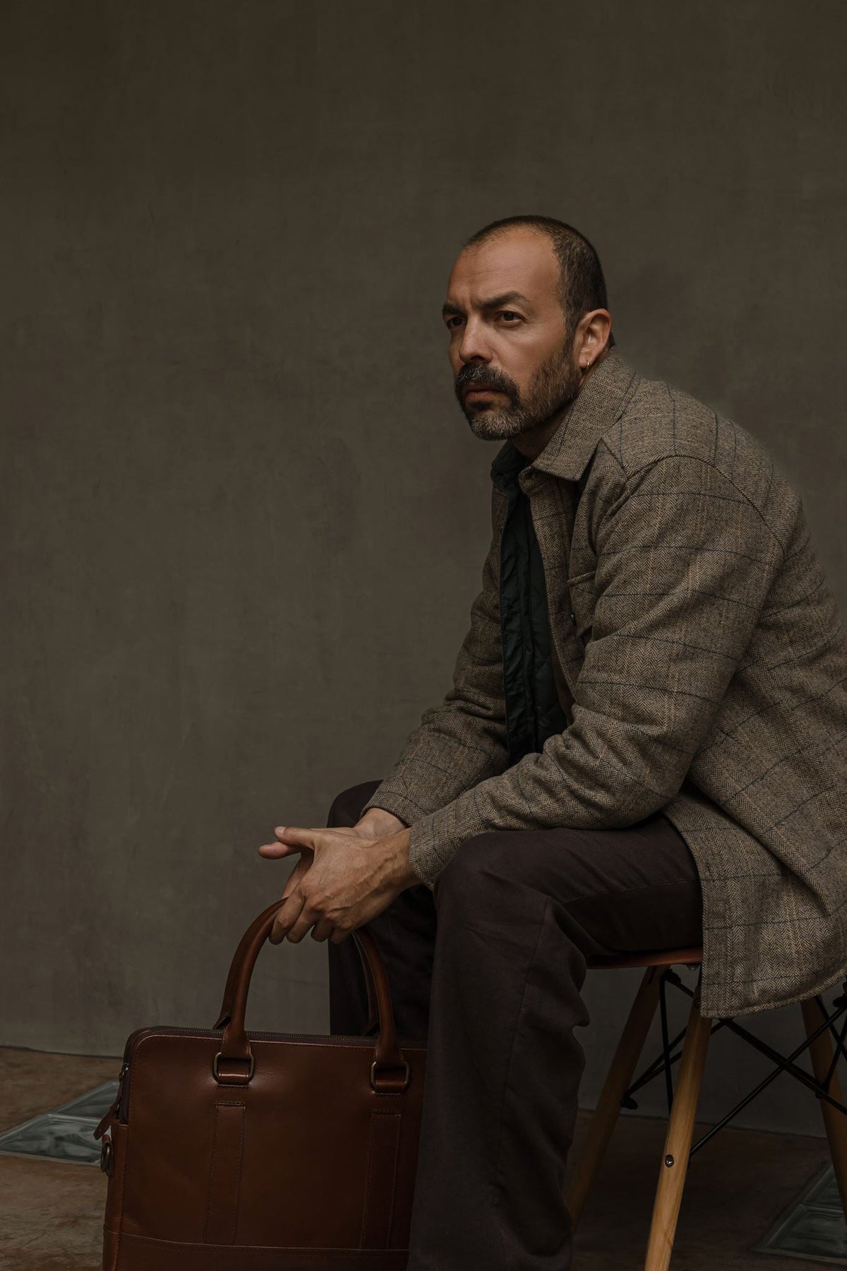 Jack Andrews wool shirt jac, seated beside a leather bag