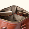 Close-up image of an unzipped tan leather duffle bag, highlighting its internal pockets and organizational compartments.