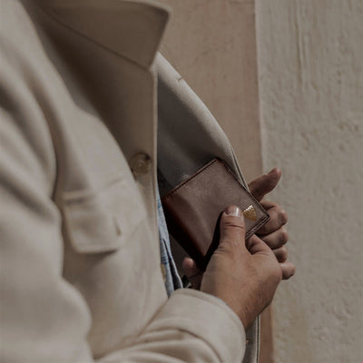 Man slipping the Jefferson Leather Bifold Wallet in Elderwood Brown into his jacket pocket.