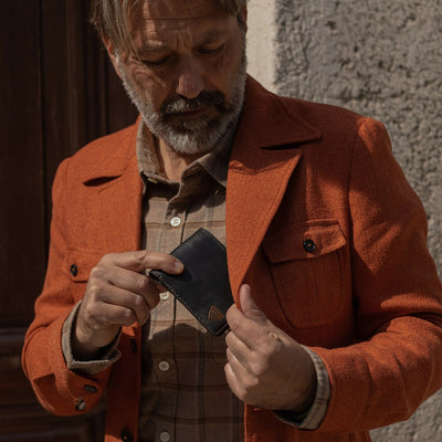 Man in an orange jacket taking a card from the Jefferson Leather Bifold Wallet in Vintage Black.