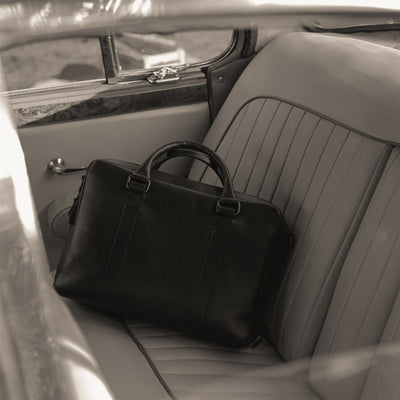 The Jefferson Leather Briefcase in Vintage Black on the back seat of a vintage car.