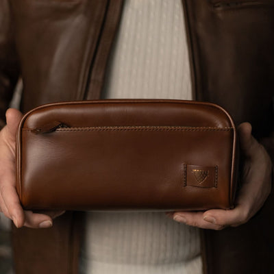 Man holding the Jefferson Leather Dopp Kit in Elderwood Brown in both hands.