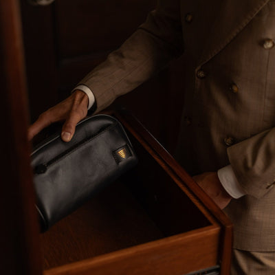 Man placing the Jefferson Leather Dopp Kit in Vintage Black into a dresser drawer.