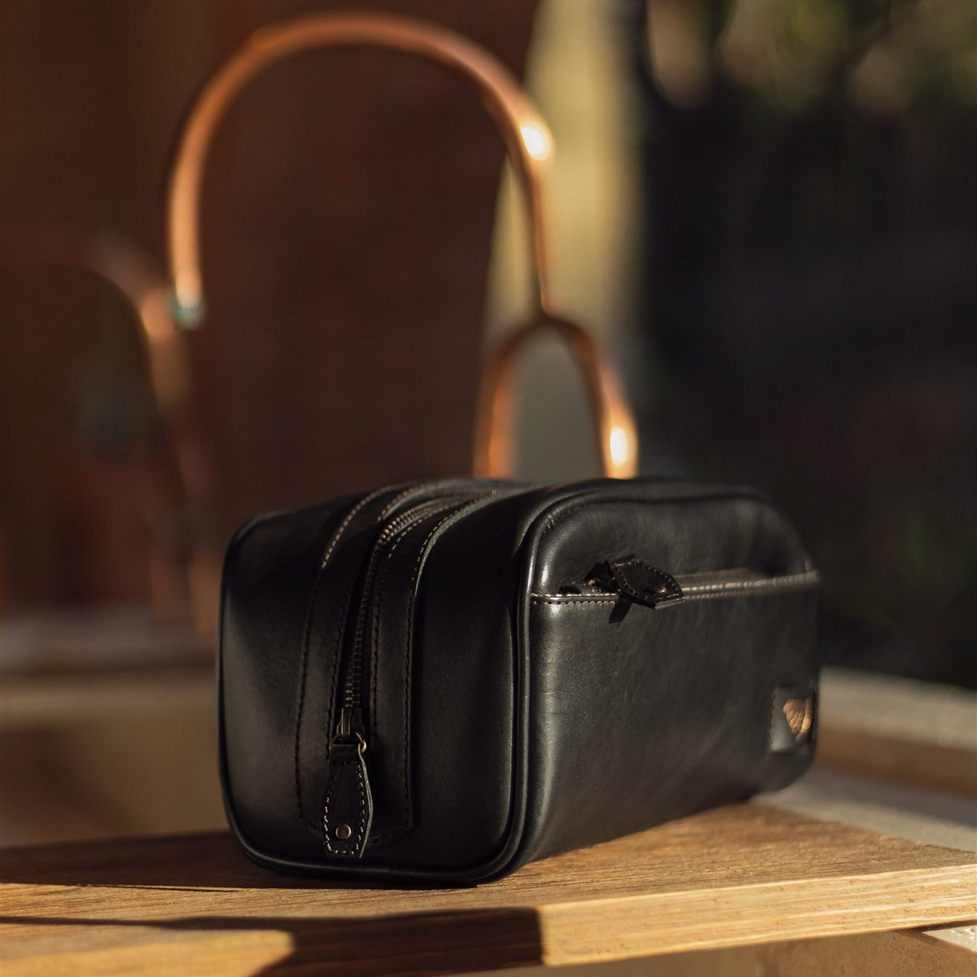 Jefferson Leather Dopp Kit in Vintage Black on a wooden shelf in warm light.