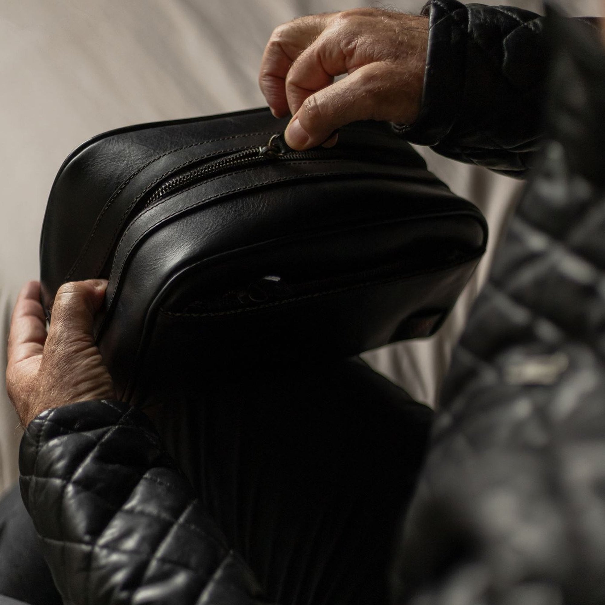 Hands unzipping the Jefferson Leather Dopp Kit in Vintage Black.