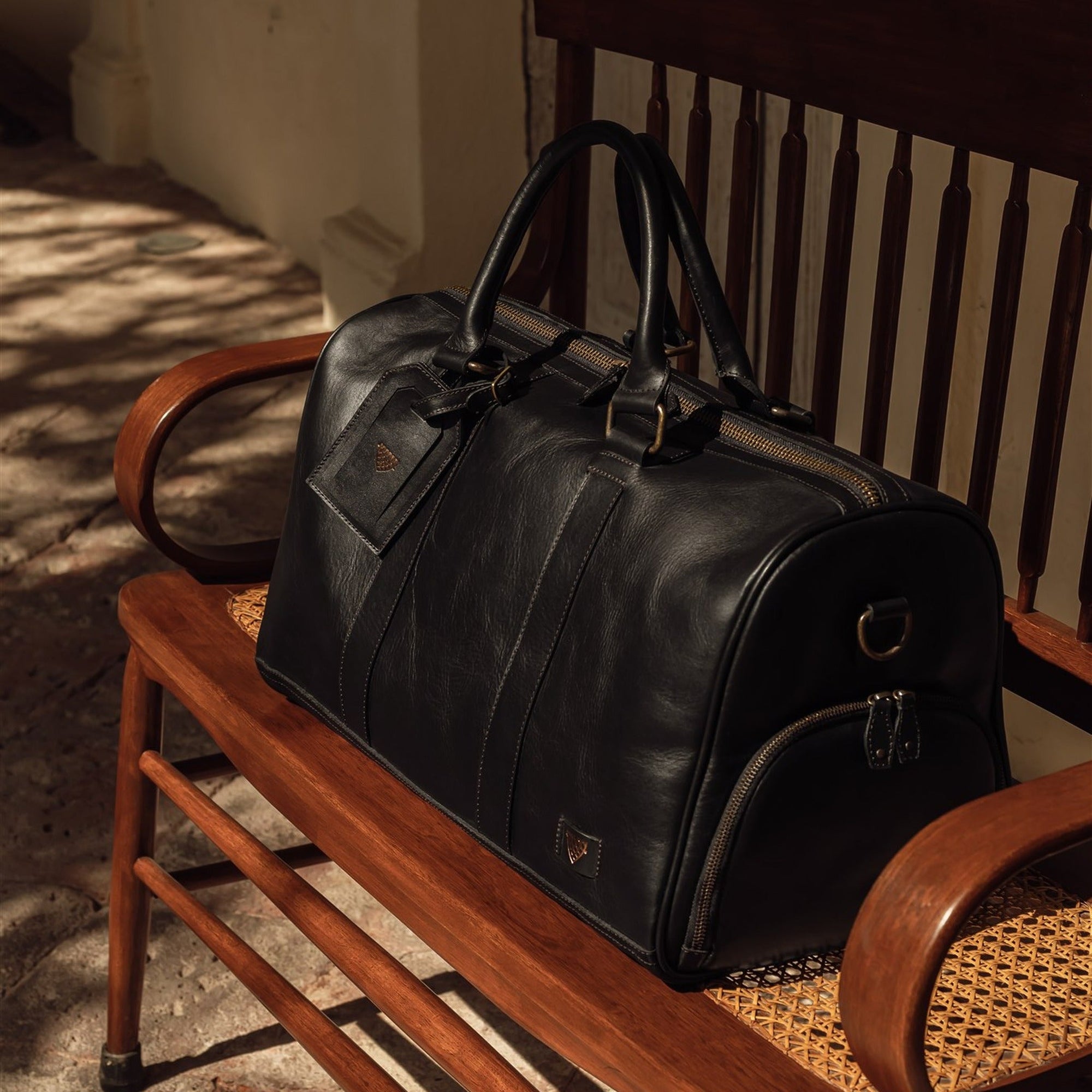 Jefferson Leather Duffle in Vintage Black resting on a wooden bench