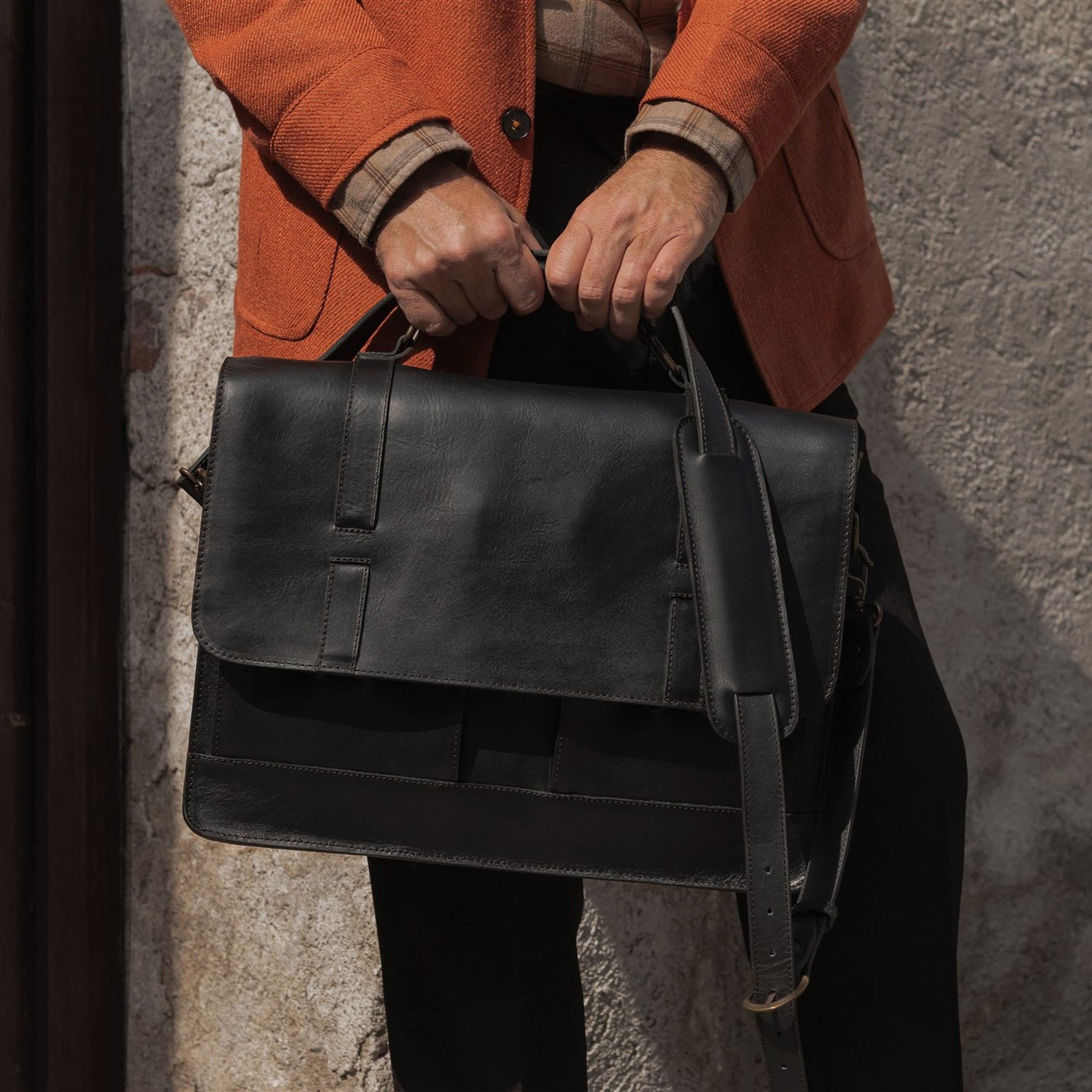 Man holding the Jefferson Leather Messenger Bag in Vintage Black by its top handle.