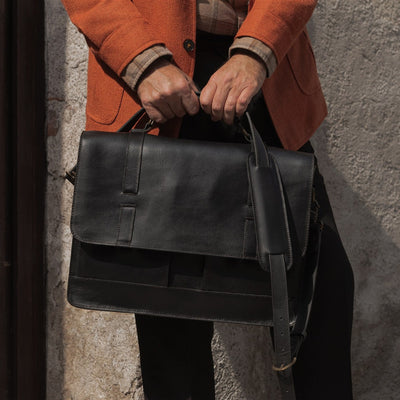 Man holding the Jefferson Leather Messenger Bag in Vintage Black by its top handle.