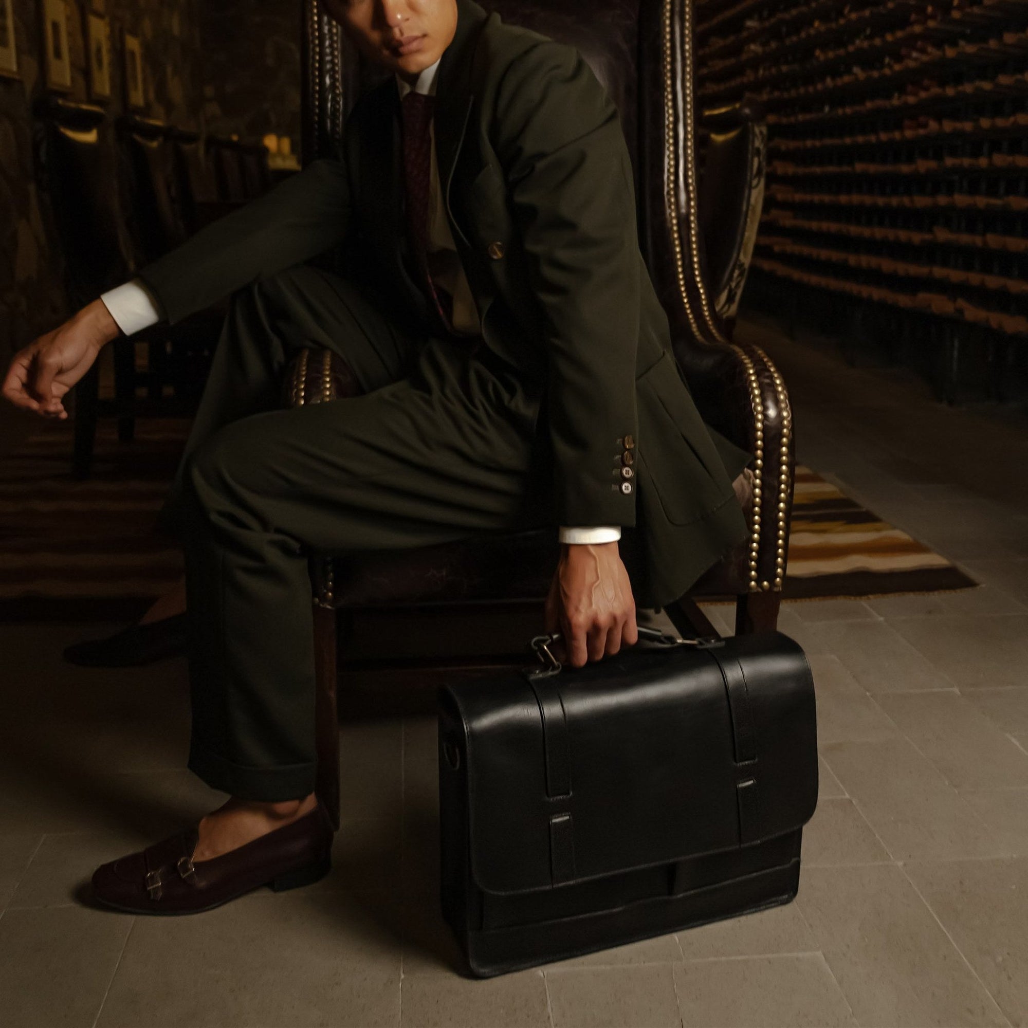 Man seated with the Jefferson Leather Messenger Bag in Vintage Black at his feet.