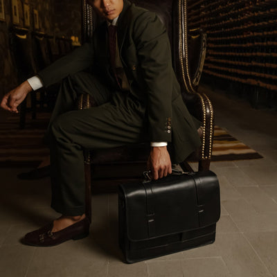 Man seated with the Jefferson Leather Messenger Bag in Vintage Black at his feet.