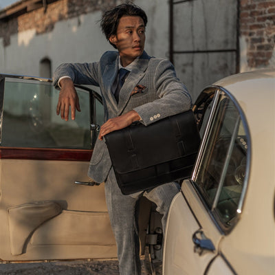 Man leaning on a vintage car with the Jefferson Leather Messenger Bag in Vintage Black.