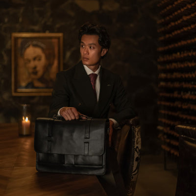 Man seated in a wine cellar with the Jefferson Leather Messenger Bag in Vintage Black.
