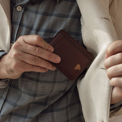 Man tucking the Jefferson Leather Slim ID Wallet in Elderwood Brown into his inside jacket pocket.