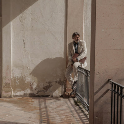 Man seated by a sunlit wall with the Jefferson Leather Travel Portfolio in Elderwood Brown.
