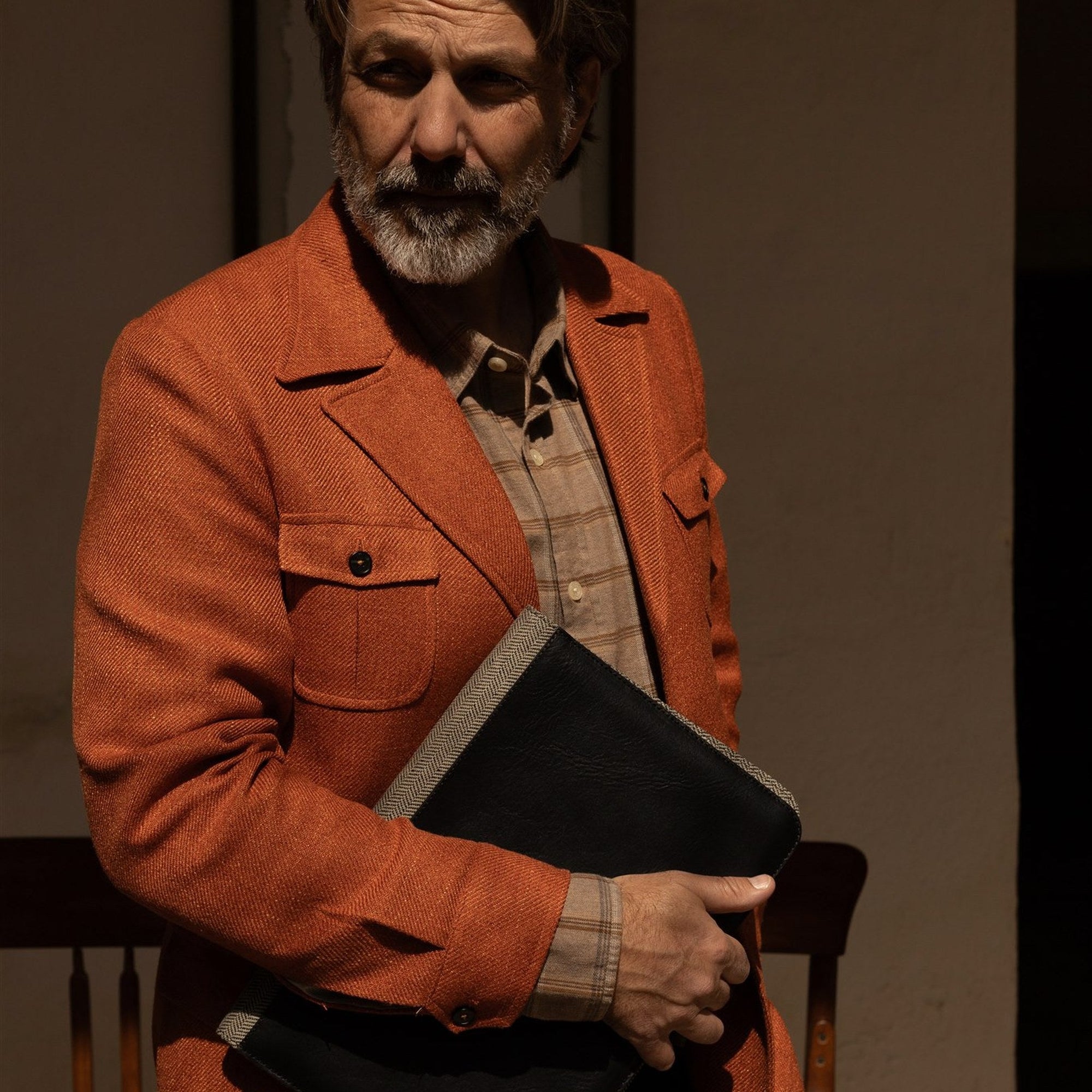 Man in an orange jacket with the Jefferson Leather Travel Portfolio in Vintage Black under his arm.