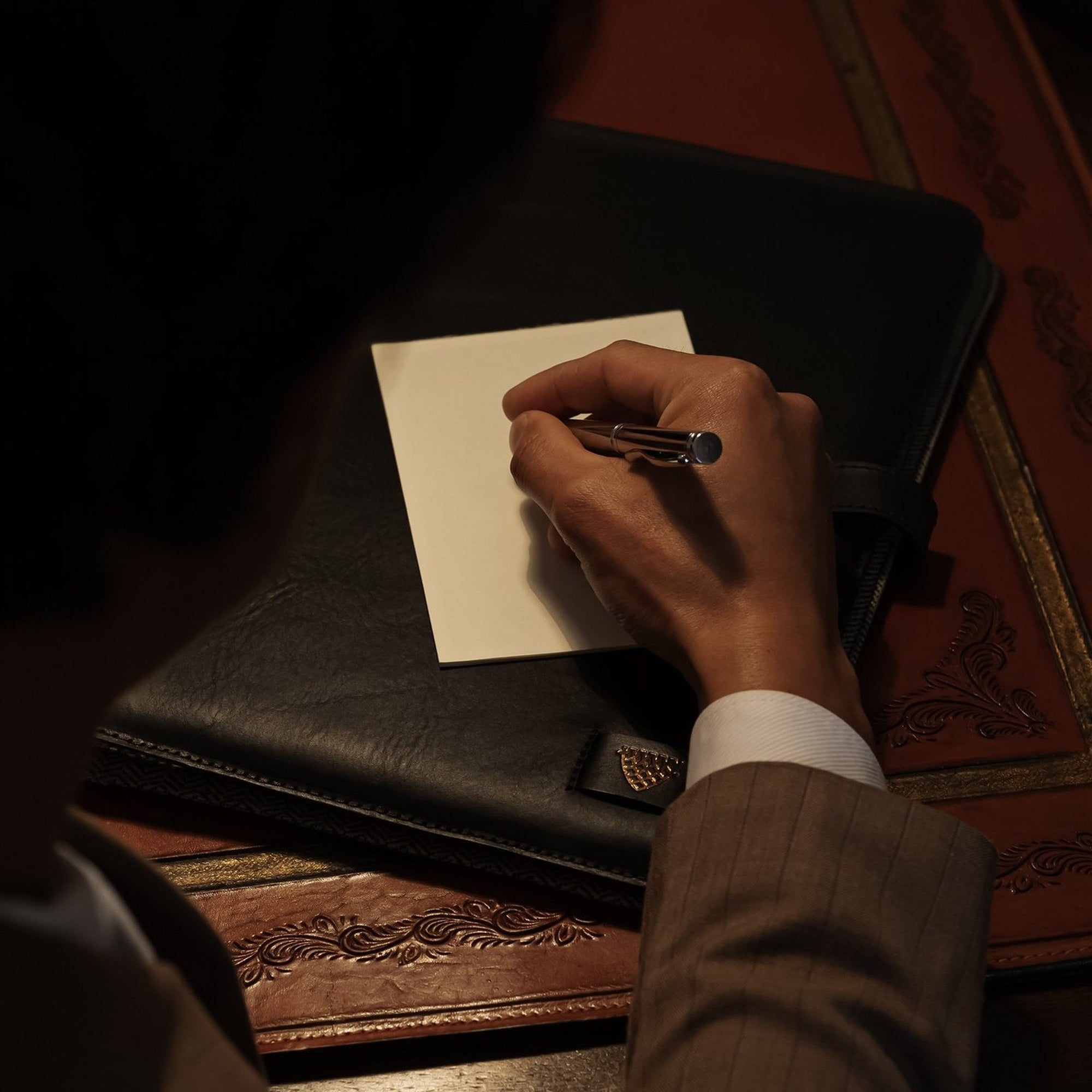 Hand writing a note on the Jefferson Leather Travel Portfolio in Vintage Black.
