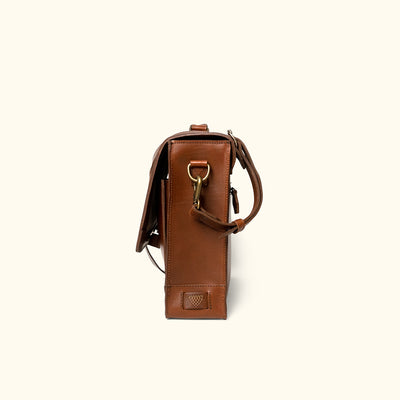 Brown leather bag with a strap on a white background